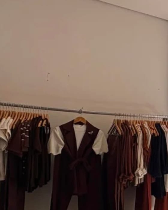 Interior da loja MASÔ, com araras de roupas femininas e um conjunto marsala em destaque